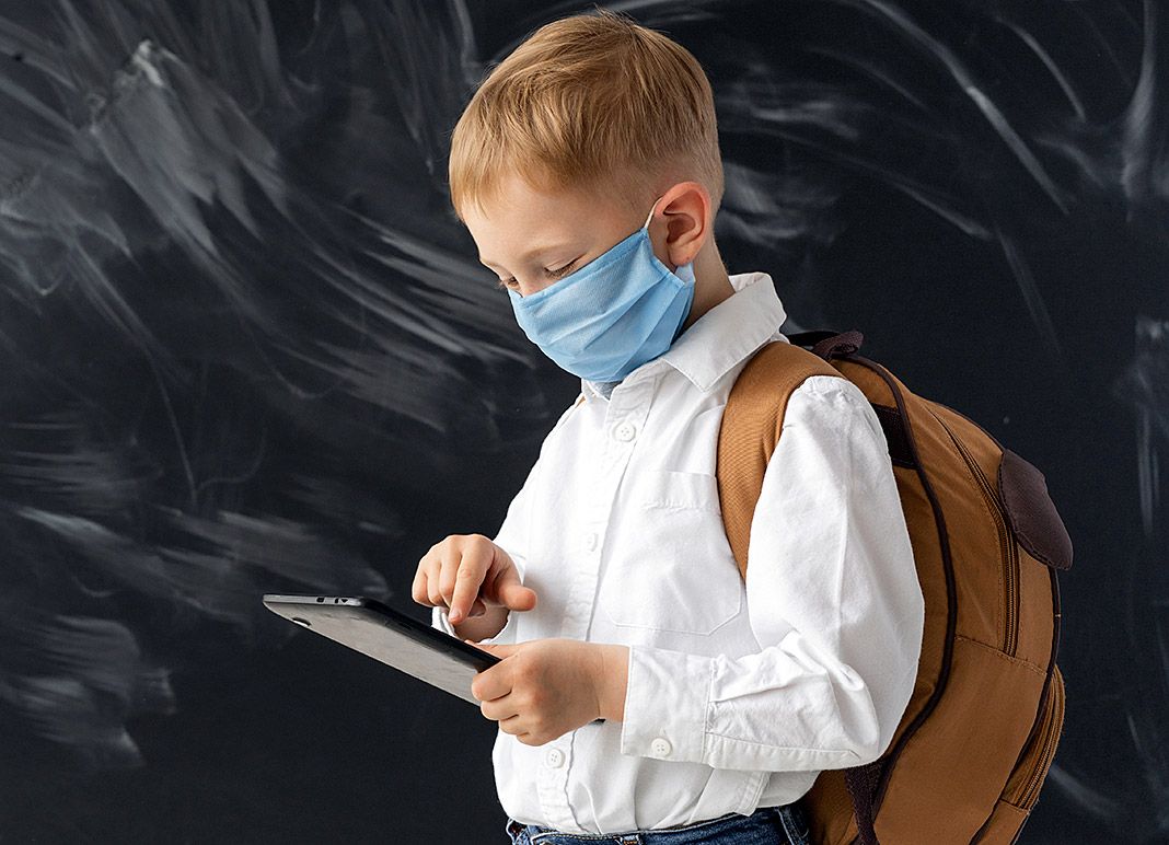 Niño en la escuela con mascarilla y tablet