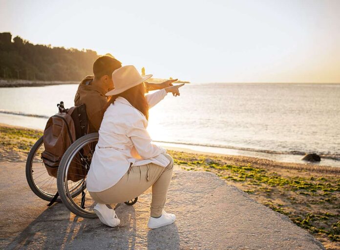 Mujer y hombre en silla de ruedas en la playa
