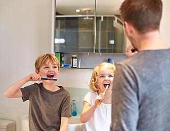 Padre enseña a sus hijos a lavarse los dientes