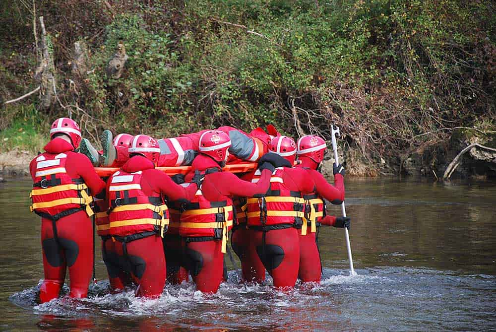 Equipo de la Cruz Roja trasladando a un herido en unas inundaciones