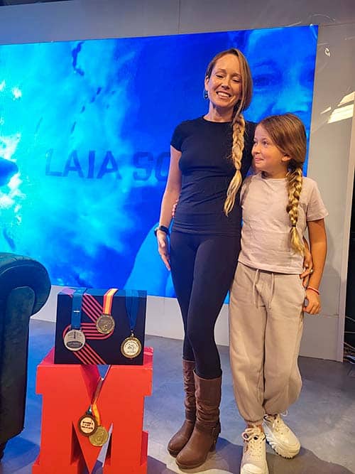 Laia Sopeña, apneista, con su hija Lea, junto a varias de sus medallas conseguidas.