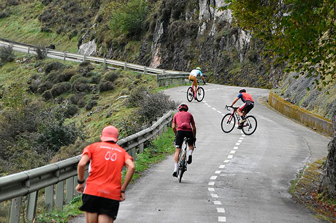 Corredor y ciclistas subiendo las pendientes del Angliru