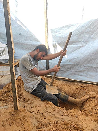 Waseem construye un baño para él y su familia tras haber sido  evacuado al sur. La tienda que ha conseguido ronda los 1.500 €.